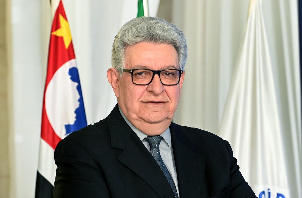 Fotografia do presidente Sérgio Bisogni, com as bandeiras de Campinas, do Estado de São Paulo e do Brasil ao fundo.