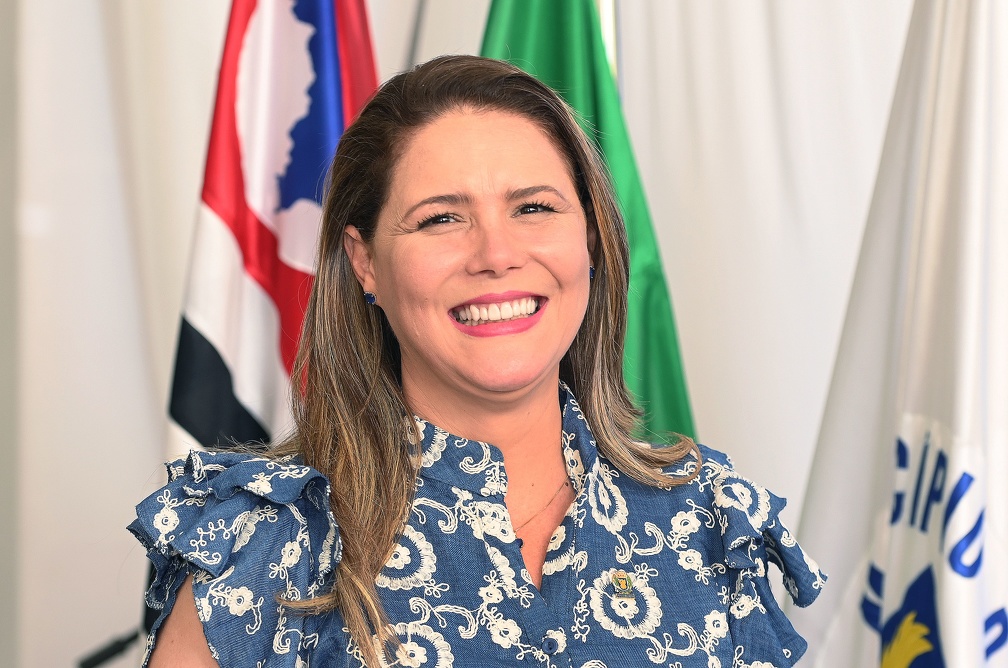 Fotografia da secretária Vandecleya Elvira do Carmo Silva Moro, com bandeiras do Estado de São Paulo, do Brasil e de Campinas ao fundo