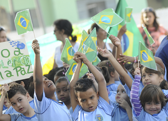 Crianças de braços ergudos durante desfile
