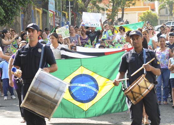 Guardas municipais tocam repique à frente de bandeira do Brasil durante desfile
