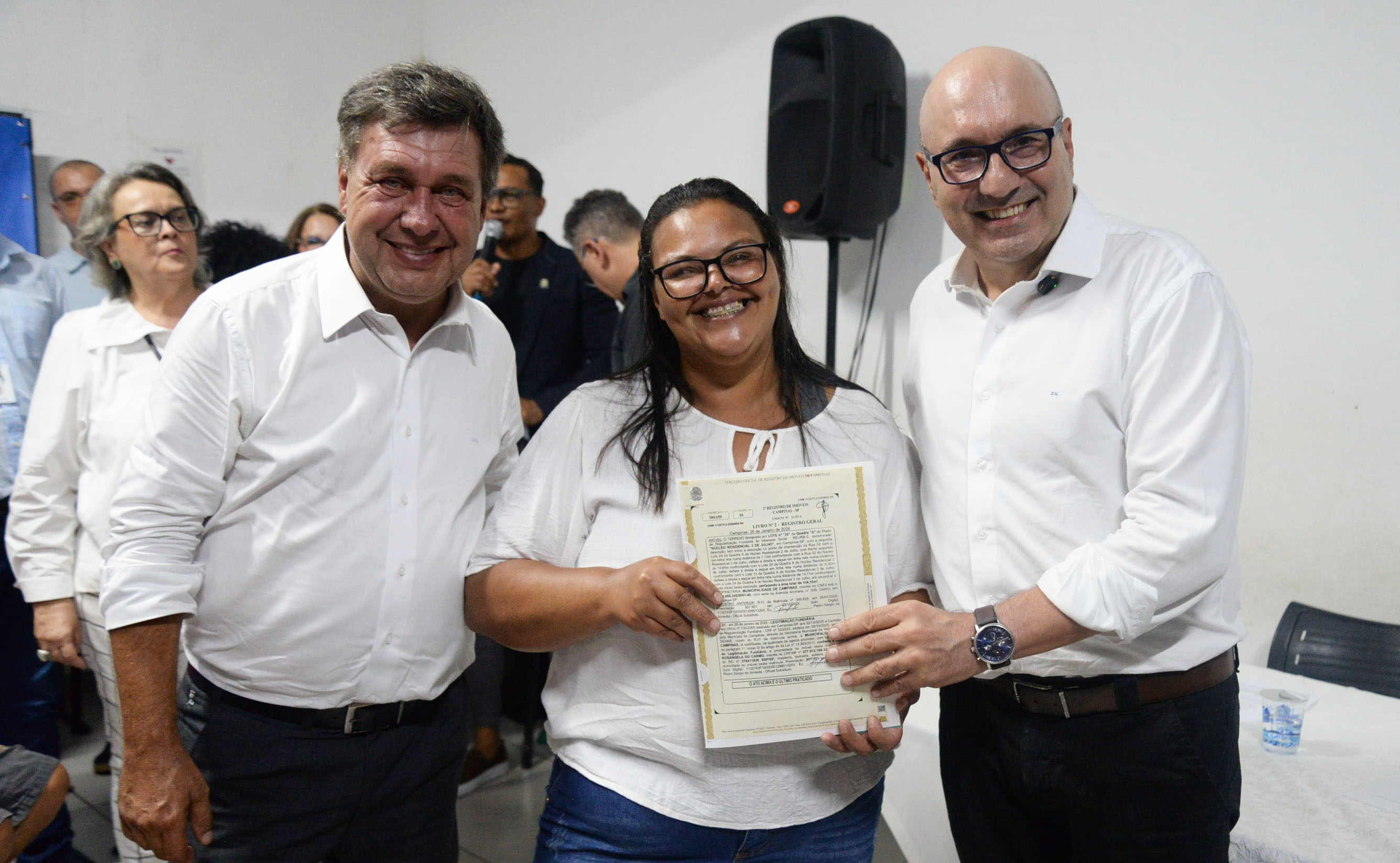 Moradora mostra a matrícula recebida pelo secretário de Habitação, Luiz Henrique Cirilo e o prefeito Dário Saadi  