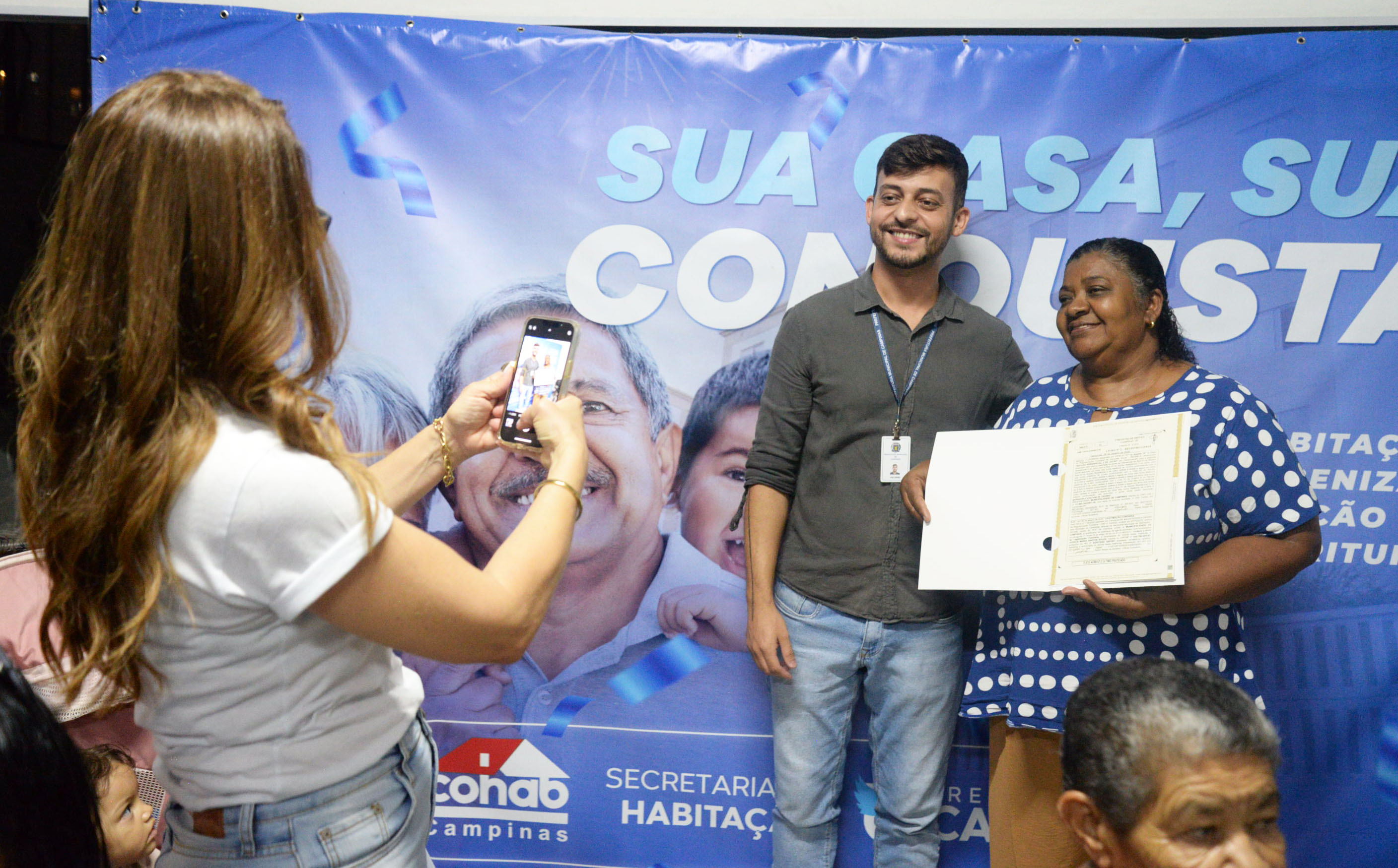 Famílias, com o documento em mãos, comemoram conquista 