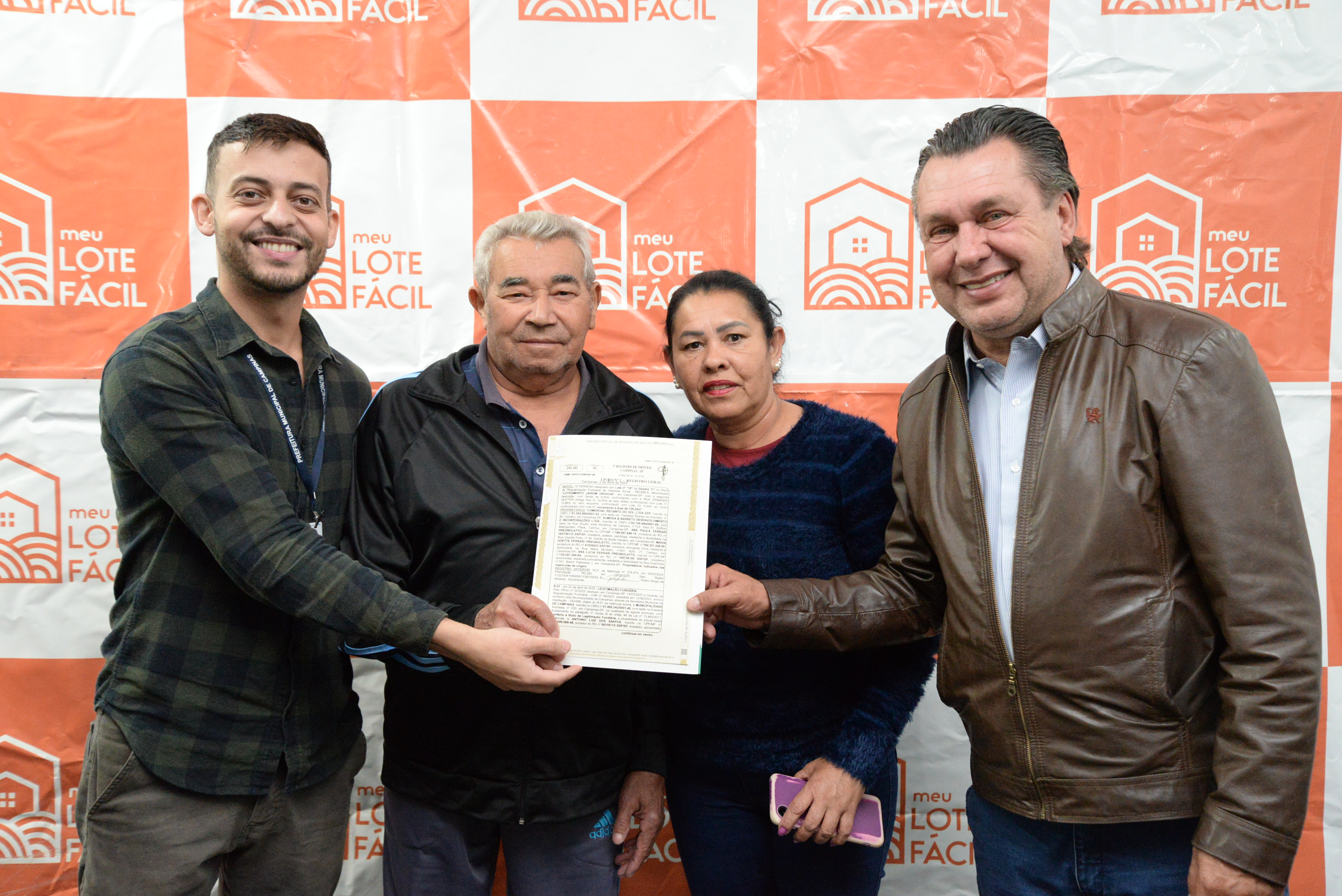 Família recebe documento do imóvel