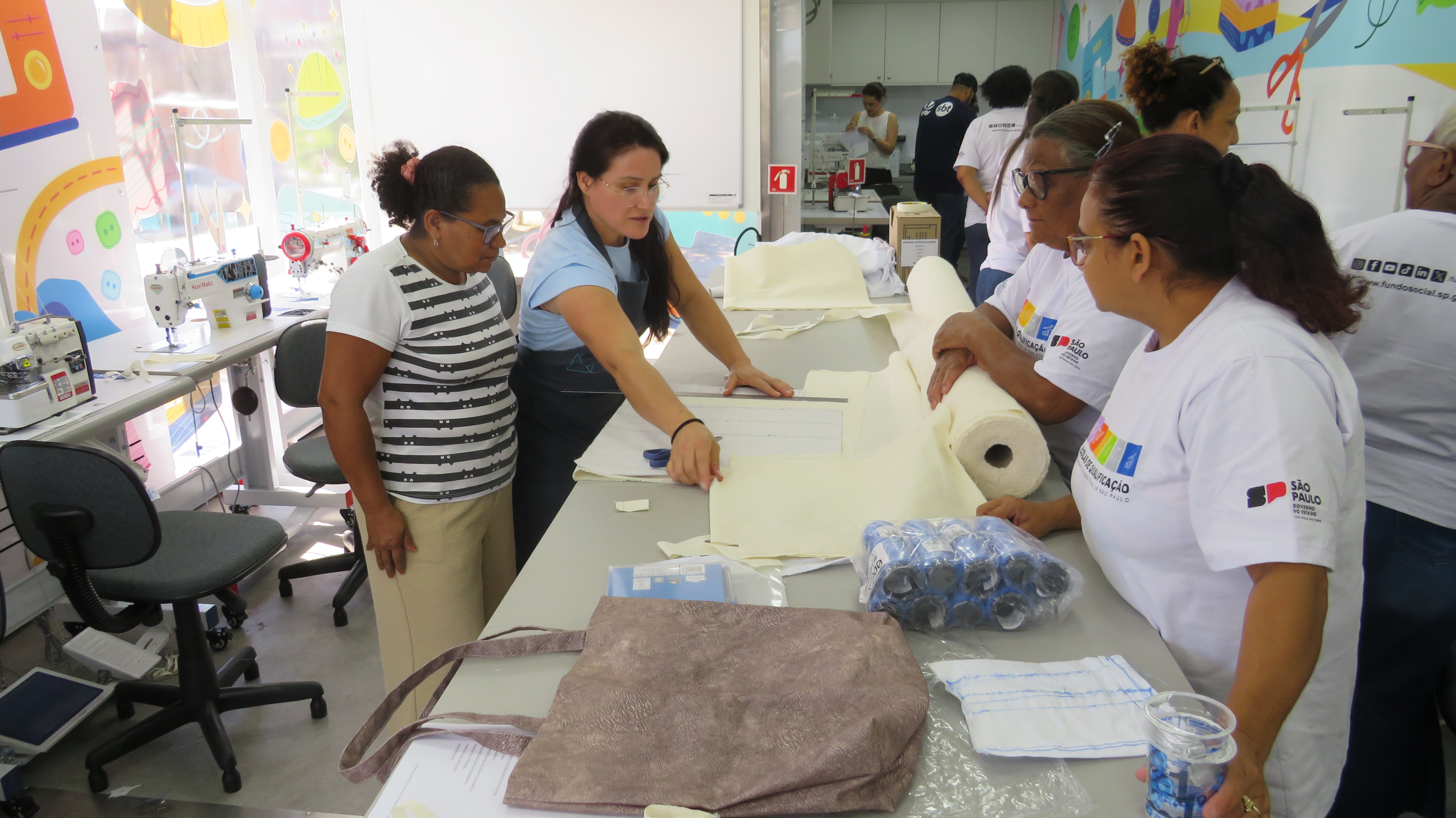 A professora Osana Raquel Cavalari (de avental azul) tem prática no ensino da costura e fica atenta na orientação às alunas
