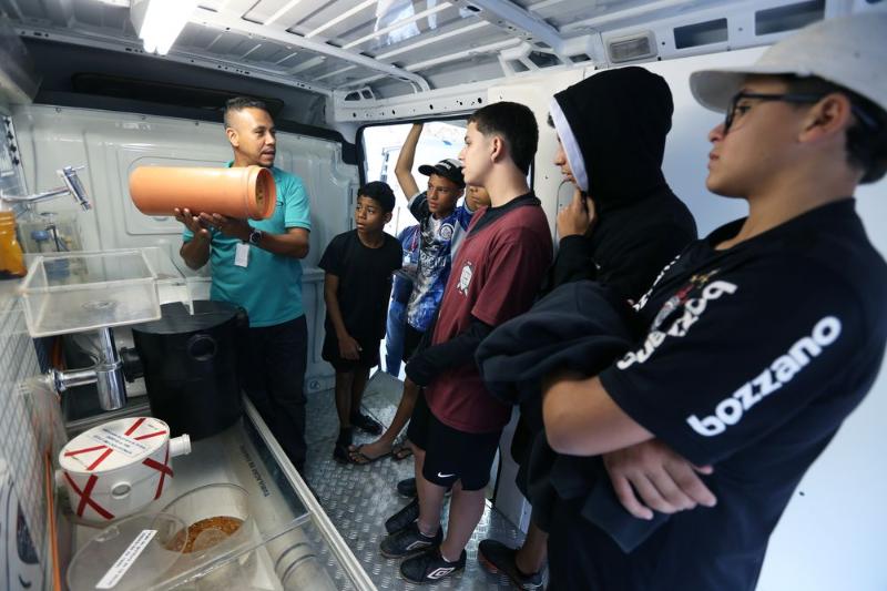 Alunos da Escola Estadual Professora Eunice Virginia Ramos Navero assistem à explicação sobre o lançamento consciente do esgoto na unidade móvel do Programa CASA