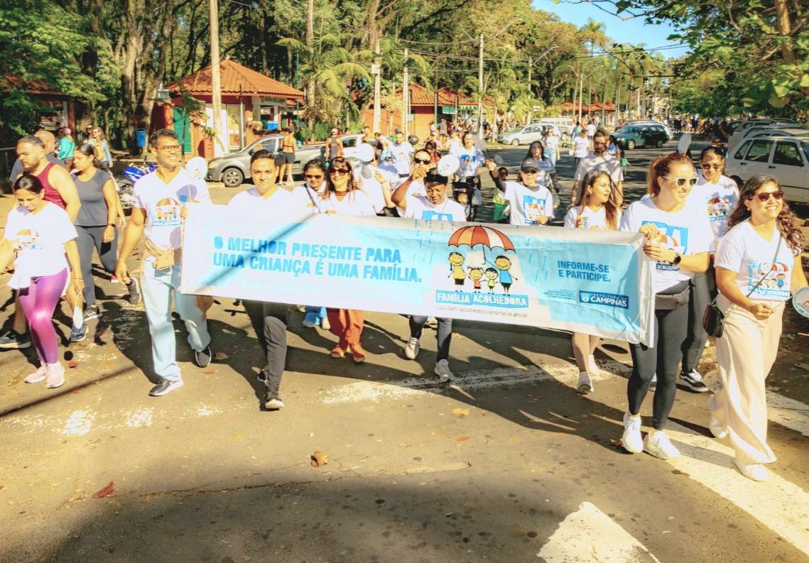 Mães e pais acolhedores com o cartaz-convite: "O melhor presente para uma criança é uma família”