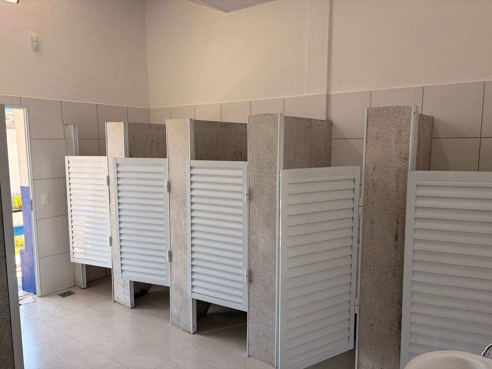 Os vestiários do albergue municipal ganharam cabines individuais, divisórias de granilite e portas de alumínio branco, além de piso e revestimento cerâmico padronizados