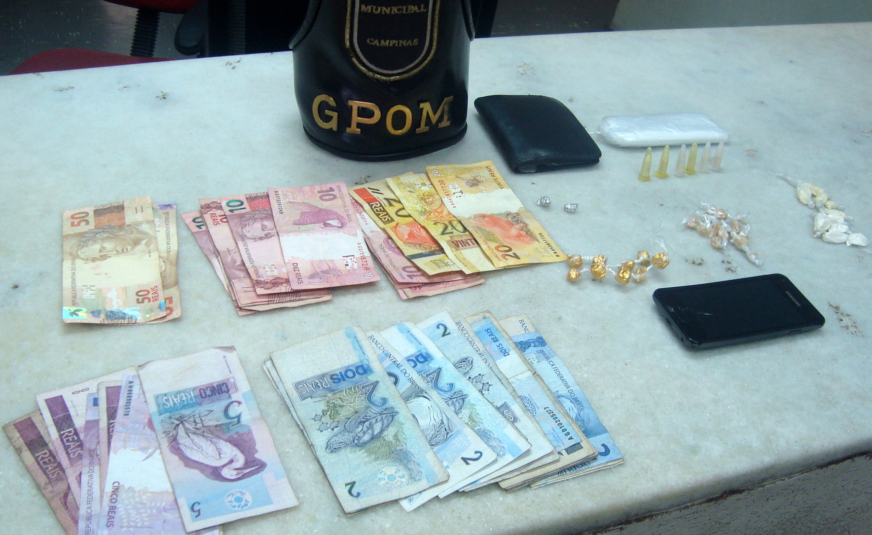 Cédulas, celular e drogas apreendidos