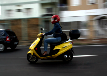 Foto com motociclista trafegando na via