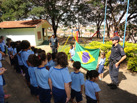 Crianças assistem apresentação dos GMs sobre a bandeira do Brasil