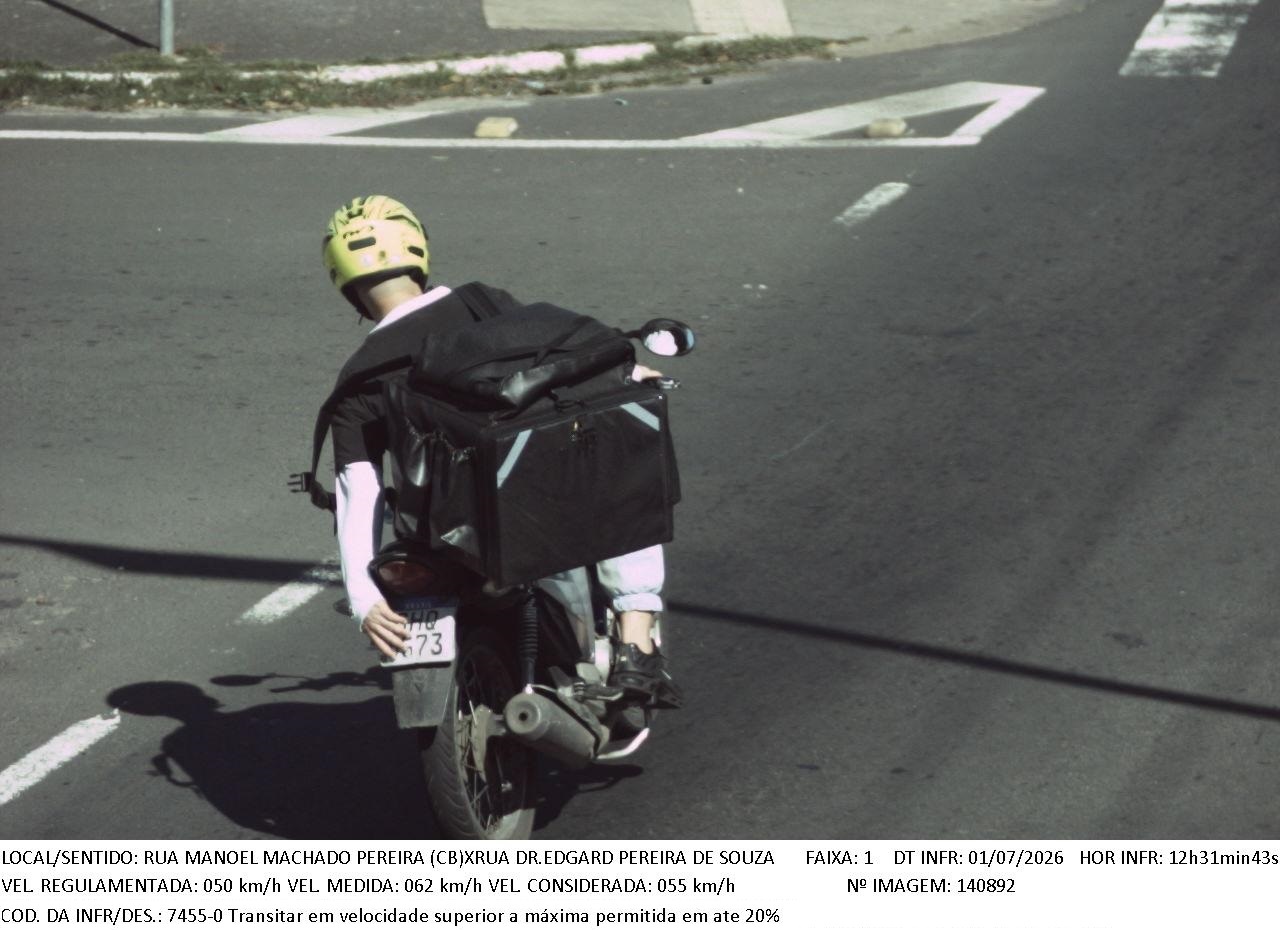Motociclista, que usa uma bag de entrega, cobre a placa com as mãos ao passar pelo equipamento